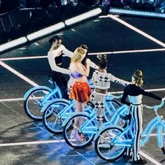 several people standing around on bikes with blue lights in the middle of them and one person holding hands