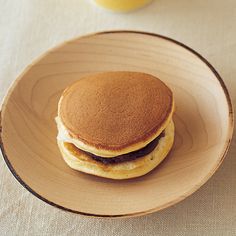 a stack of pancakes sitting on top of a wooden plate next to a glass of orange juice