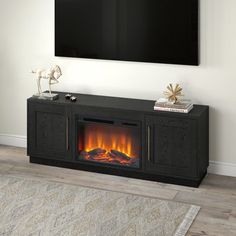 an entertainment center with a fireplace and flat screen tv mounted on the wall above it