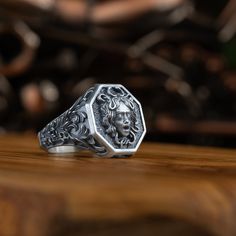 a silver ring with a lion head on it sitting on top of a wooden table