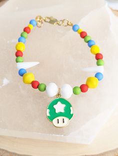 This Mario Brothers inspired bracelet features a Mushroom Head charm, which is nicely fashioned with multicolored beads, a lobster claw clasp, and extender chain. Check out the rest of our shop for more 80s and 90s nostalgia, gamer jewelry! (Our prices include the fee for shipping) Mario Bracelet, Mario Kart Kandi Cuff, Mario Jewelry, Mushroom Necklace Beads, Mushroom Necklace Bead, Gamer Jewelry, Pokemon Store, Mushroom Head, Mario Brothers