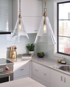 two pendant lights hanging over a kitchen counter