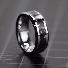 a black and white wedding ring with silver inlays on the inside of it