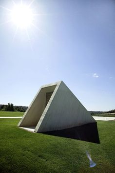 the sun shines brightly over a sculpture on top of green grass in front of a blue sky