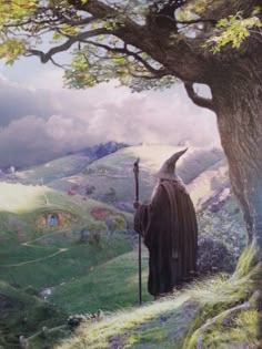 the hobbit character is standing in front of a tree and holding a staff