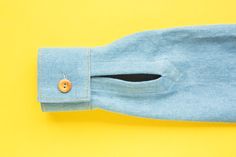 a blue shirt with a wooden button on the front and side, sitting against a yellow background