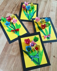 four pieces of paper with flowers on them sitting on a wooden floor next to each other