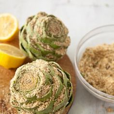 some food is sitting on a cutting board next to lemons and seasoning powder