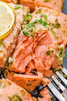 a fork with salmon on it next to a piece of lemon and broccoli