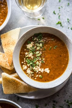 a white bowl filled with soup next to some pita bread