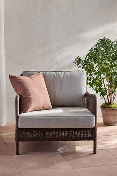 a couch sitting on top of a tiled floor next to a potted plant