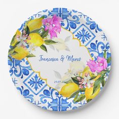 a blue and white plate with lemons, flowers and leaves painted on the side