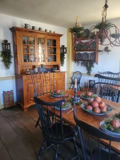 a wooden table topped with plates and bowls filled with fruit next to a hutch