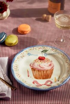 a plate with a cupcake on it sitting on a table next to wine glasses