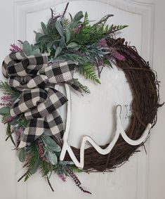 a wreath is hanging on the front door with an antler and ribbon around it