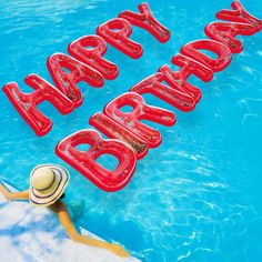 a woman sitting on the edge of a pool next to a sign that says happy birthday