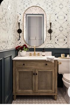 a white toilet sitting next to a wooden sink vanity in a bathroom under a mirror