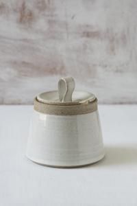 a white ceramic container with two spoons in the top and one on the bottom