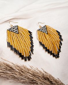 two pairs of yellow and black beaded earrings sitting on top of a white sheet