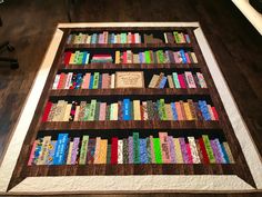 a quilted bookcase with many books on it sitting on top of a wooden floor