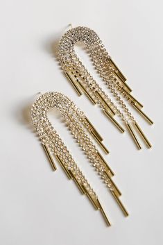 One glance is all it took for us to fall for the Callie Gold Rhinestone Fringe Earrings! These trendy earrings start with a rhinestone semi-circle stud post back and fall to rhinestone fringe chains. Add these fun earrings to a black dress + heels to add a chic touch to your date night look! Gold Plated Rhinestones Fringe Stud Post Back One Size | Length 3” Gold Crystal Earrings With Rhinestone Fringe, Gold Rhinestone Fringe Metal Jewelry, Gold Metal Jewelry With Rhinestone Fringe, Gold Earrings With Rhinestone Fringe For Evening, Black Dress Heels, Black Dress With Heels, Gold Rhinestone Earrings, Rhinestone Fringe, Ball Hairstyles