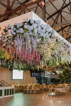 an indoor event with flowers hanging from the ceiling