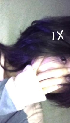 a woman with purple hair is holding her hands up to her face and the word x above her head