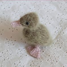 a small stuffed bird sitting on top of a white doily