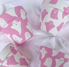 pink and white paper with ghost shapes on it's sides sitting on a bed