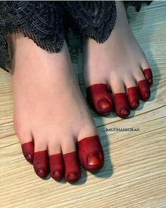 a person with red toenails standing on a wooden floor