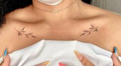 a woman with two small tattoos on her chest holding a white object in front of her face