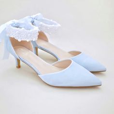 a pair of blue high heeled shoes with a bow on the toe and lace detailing