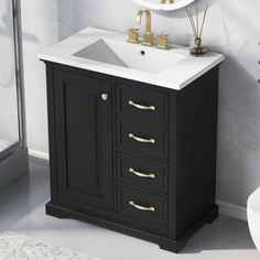 a white sink sitting under a mirror next to a black and gold cabinet in a bathroom