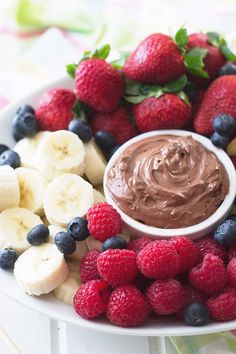 chocolate fruit dip surrounded by berries and bananas on a white plate with the words chocolate fruit dip