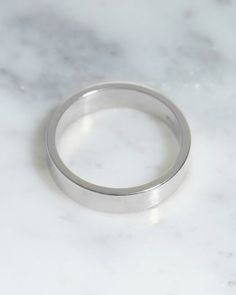 a white gold wedding ring on a marble surface