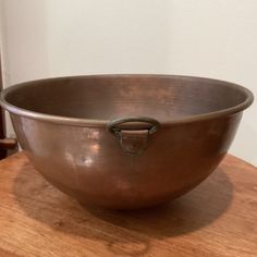 a large metal bowl sitting on top of a wooden table