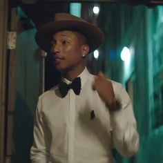 a man wearing a white shirt and bow tie standing in front of a building at night