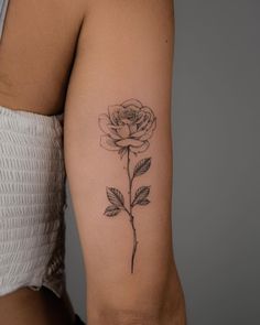 a woman's arm with a rose tattoo on the left side of her arm