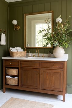 a bathroom with green walls and wooden cabinetry, white countertop, gold faucet