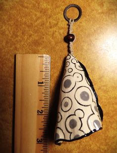 a measuring tape is next to a small bell ornament on a wooden table