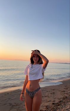 a woman standing on top of a beach next to the ocean