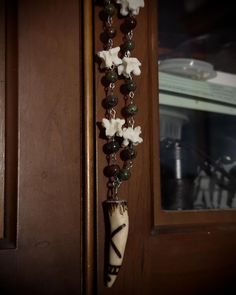 a wooden door with a long beaded necklace hanging from it's side