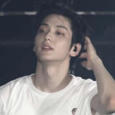 a young man is listening to music with ear buds on his ears and wearing a white t - shirt