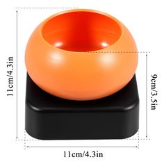 an orange ball sitting on top of a black stand next to a white background with measurements