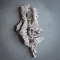 a fork and napkin on top of a gray surface with a white cloth draped around it