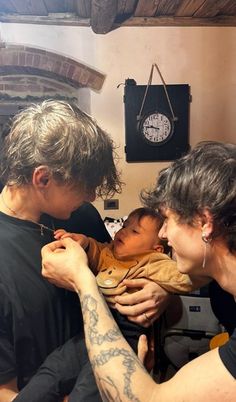 a man holding a baby in his arms while two other people look at the camera