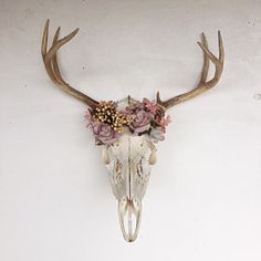 a deer skull with flowers on it's antlers is mounted to the wall