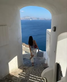 a woman standing in an archway looking out at the ocean