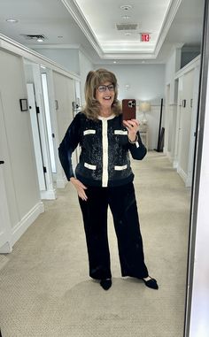 a woman taking a selfie in the mirror while wearing black and white pajamas, holding a cell phone