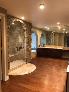 a large bathroom with a walk in shower next to a double sink vanity and wooden floors